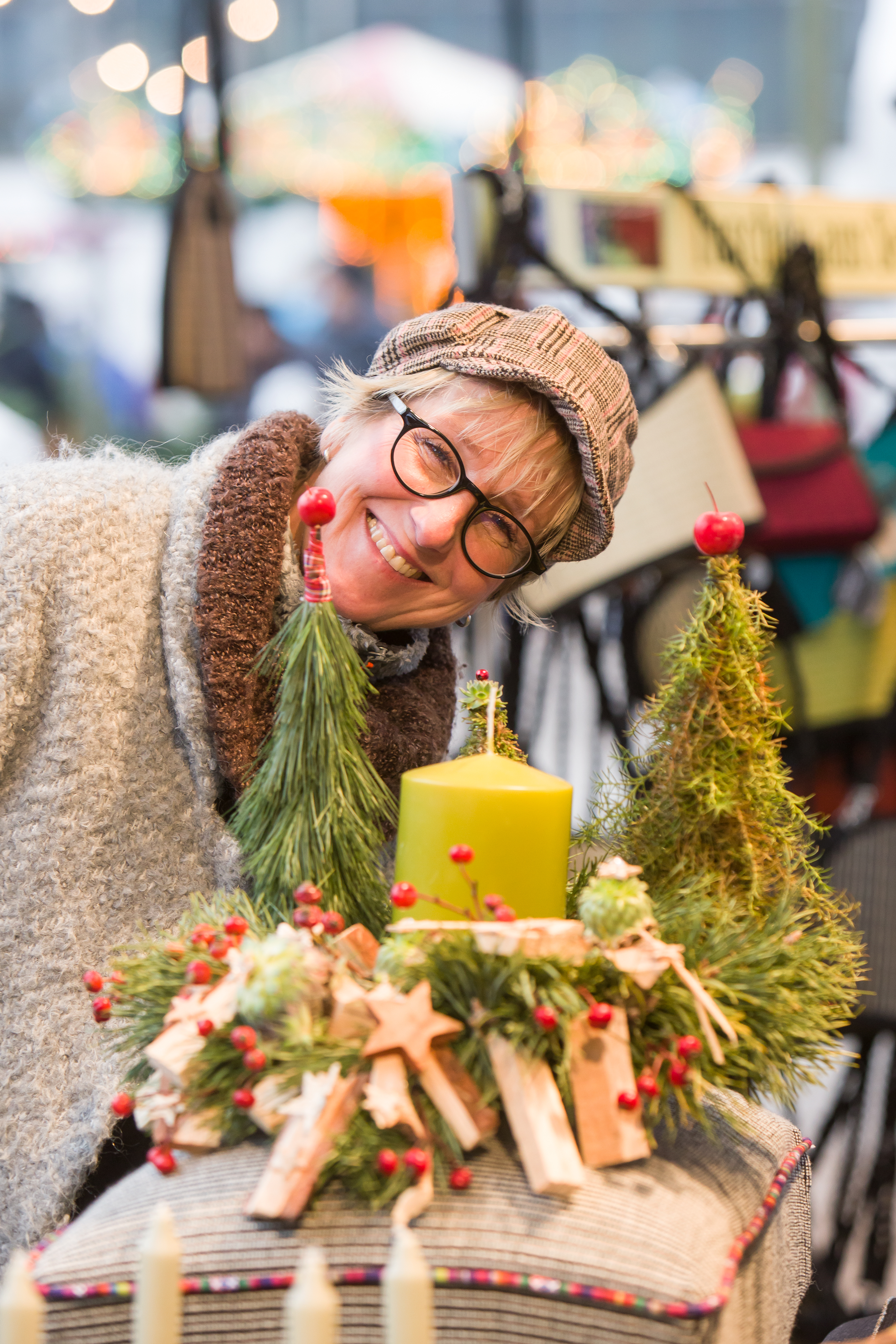 Dame mit strahlendem Lachen beugt sich über ein Adventsgesteck