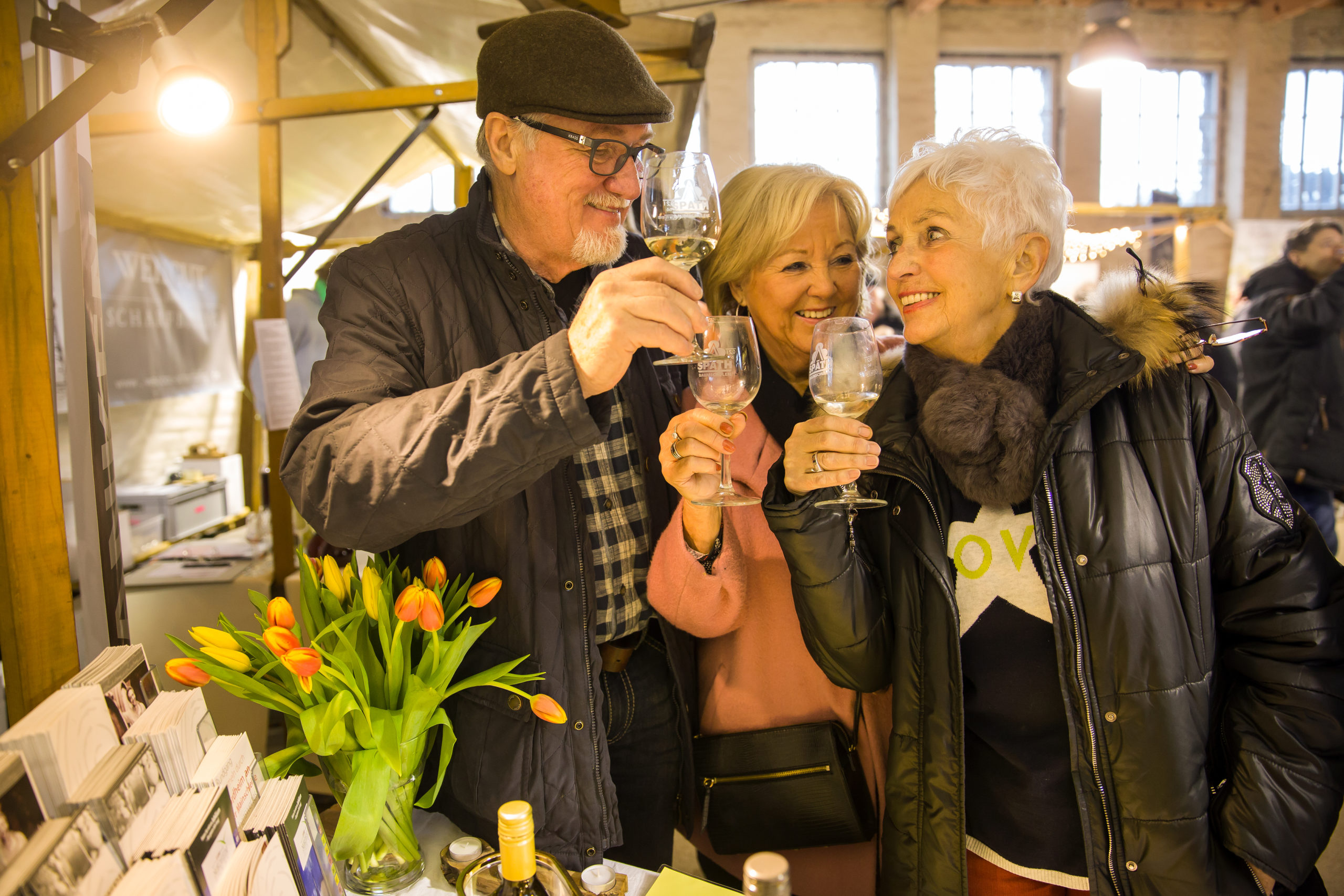 Besucher prosten sich beim Weinfest in der historischen Packhalle zu