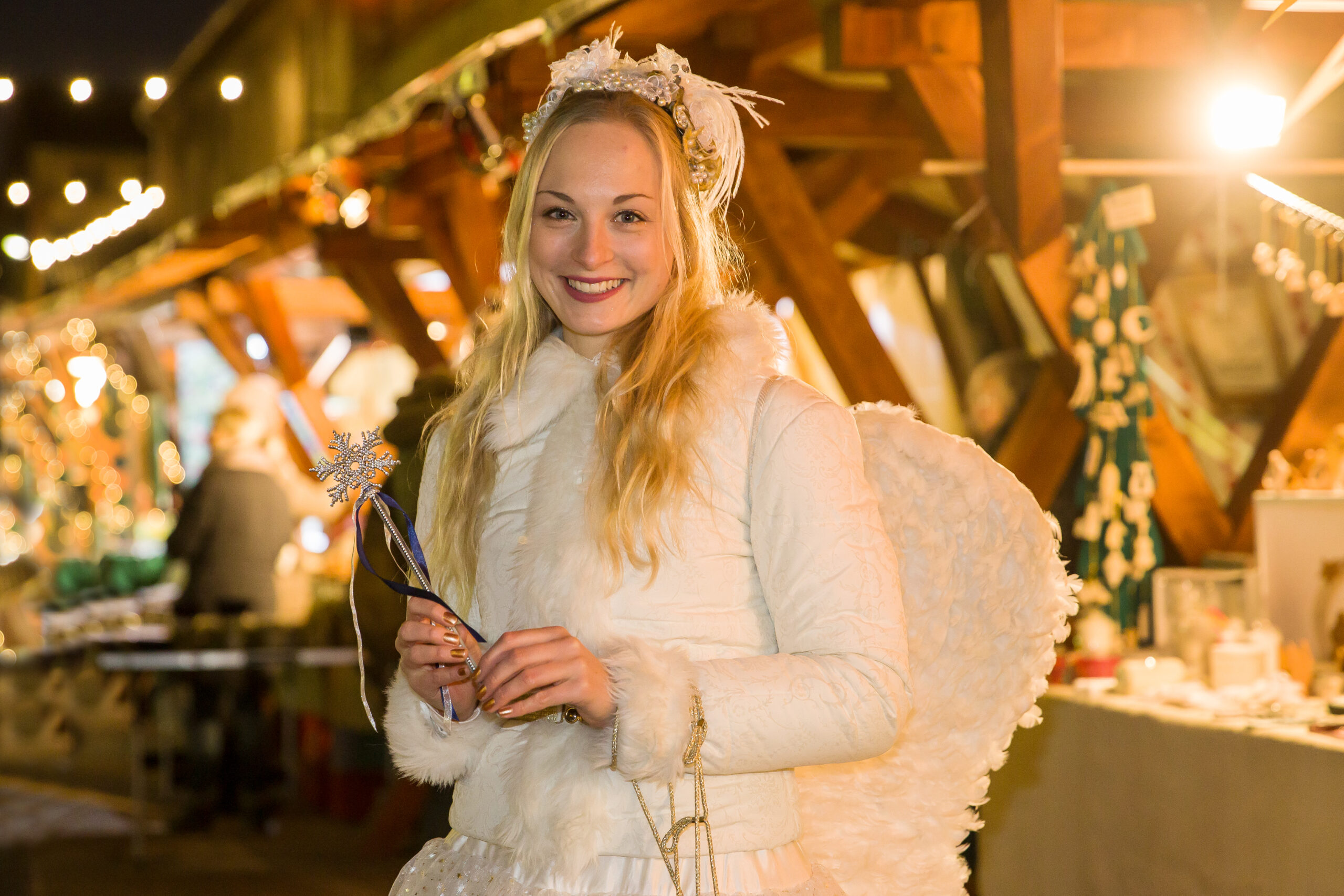 Blonder Engel vor Ständen mit Geschenkideen