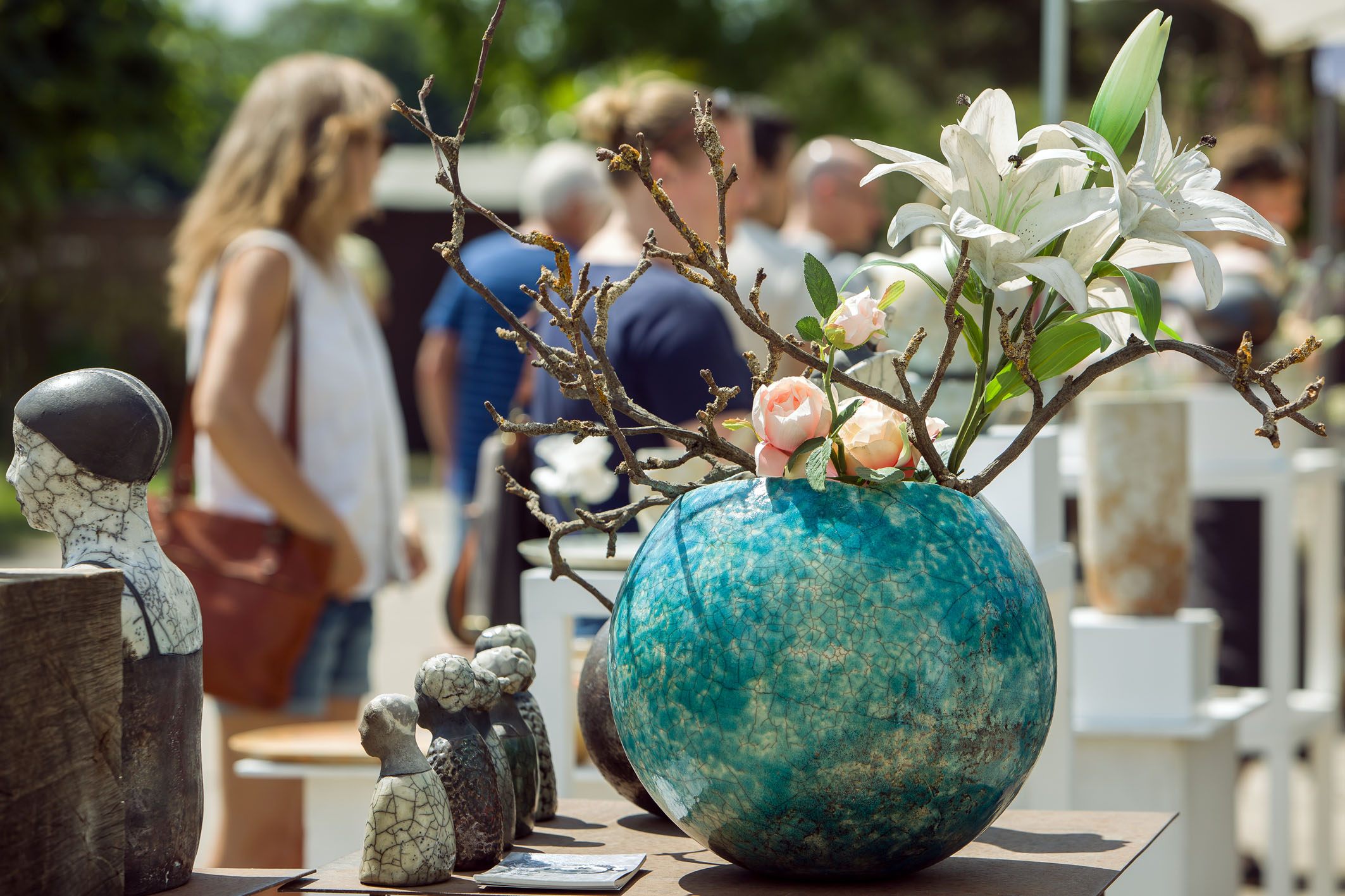 Blaue runde Töpfervase, im Hintergrund Menschen auf dem Markt