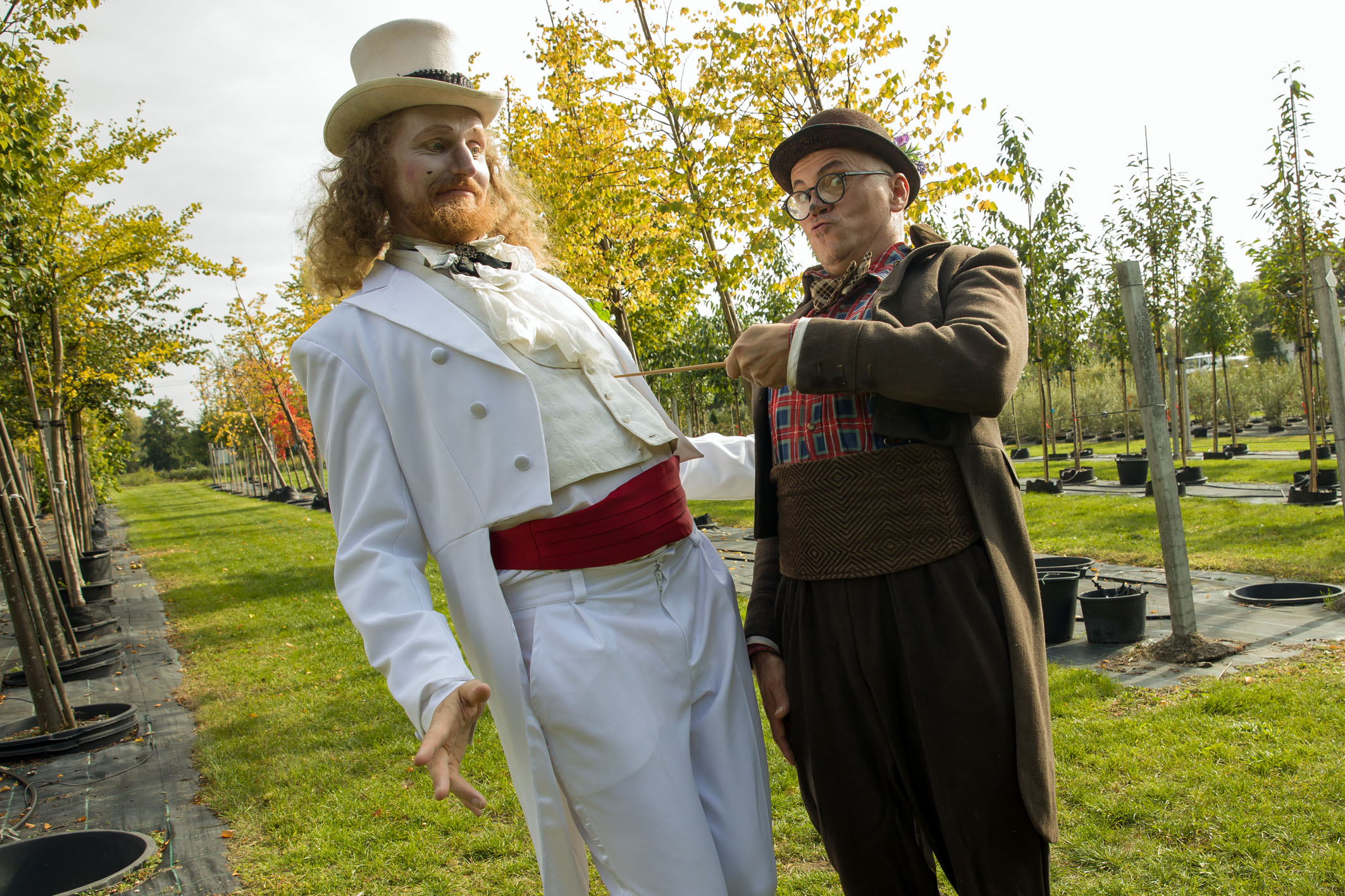 Zwei Schauspieler des Monbijou-Theaters posieren inmitten der Pflanzenproduktion der Späth'schen Baumschulen.