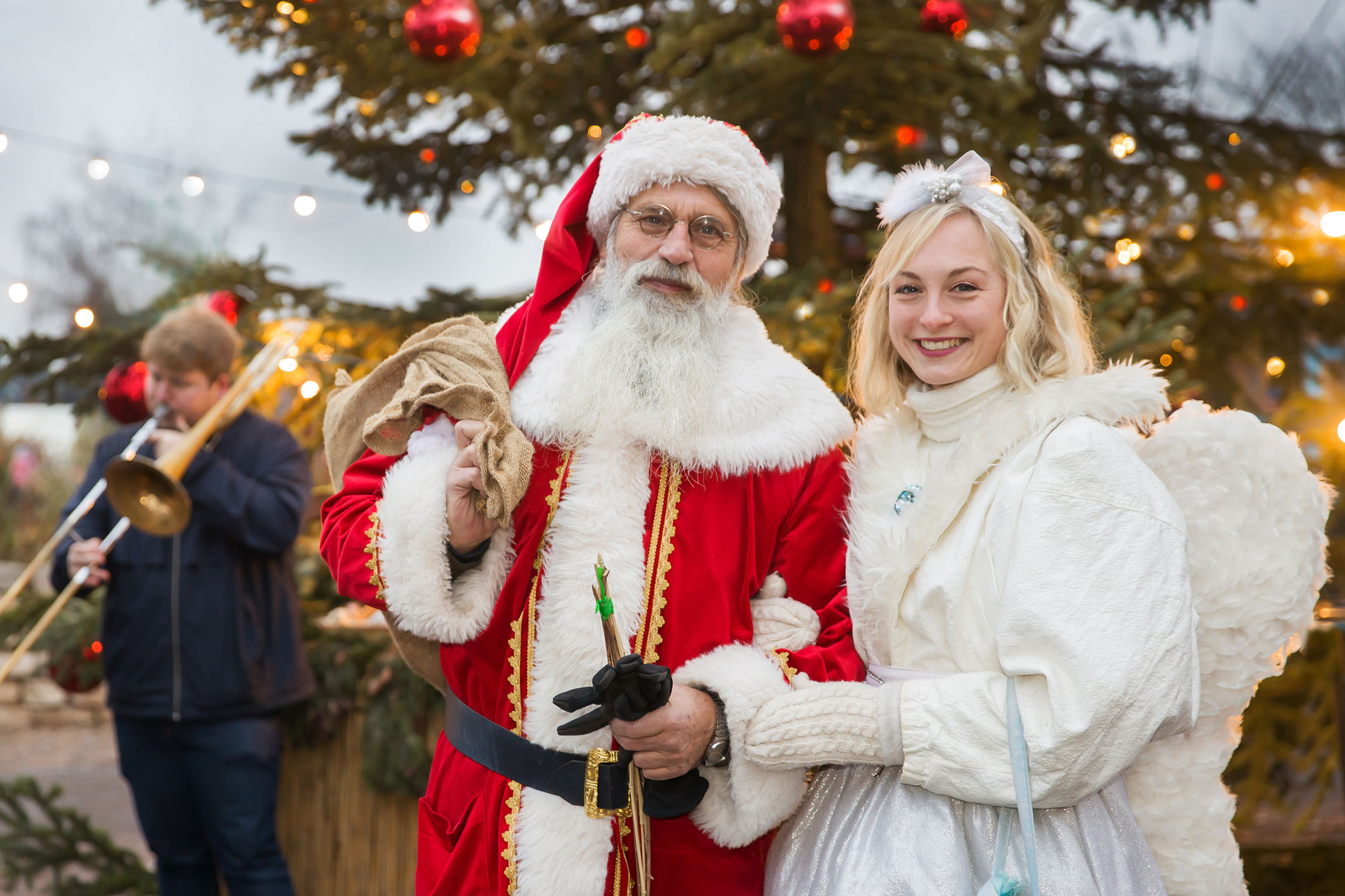Weihnachtsmann und engel vorm großen geschmückten Tannenbaum